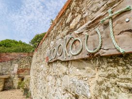 A stone wall with a wooden sign displaying the word The Lookout made of rope at Stardust in Ventnor