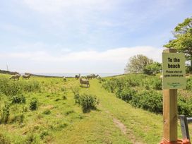 A grassy pathway with sheep and a signpost pointing to the beach at Stardust in Ventnor