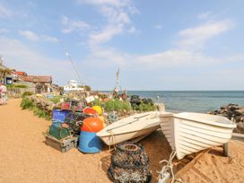 A beach with two small white boats and fishing equipment near a stone wall by the sea at Stardust in Ventnor