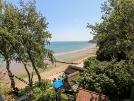 A view of a beach with boats near a thatched roof building and trees at Stardust in Ventnor