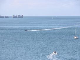 A seascape with several boats on the water and a group of rocks with a lighthouse in the distance at Stardust in Ventnor