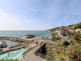 A coastal scene with a walkway, buildings, gardens, and the sea at Stardust in Ventnor