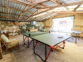 A game room with two ping pong tables foosball table chairs and stone and wooden walls at Stardust in Ventnor