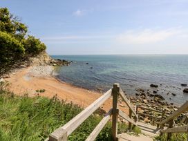 Wooden stairs leading down to a rocky beach with a cliff and ocean view at Stardust in Ventnor