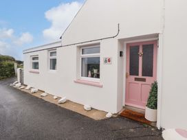An exterior view of a house with a pink door and numbered sign at Penwyn in Solva
