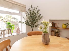 A dining room with a wooden table and a flower vase at Penwyn in Solva
