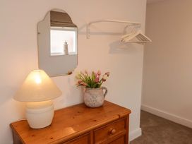 A bedroom with a lamp and flowers on a dresser at Penwyn in Solva