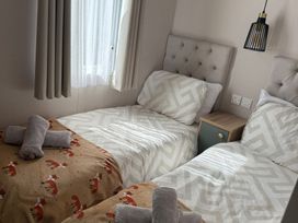 A bedroom with twin beds and a bedside table at Seren in Broughton, Cumbria