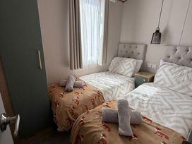 A bedroom with two beds and a wardrobe at Seren Broughton, Cumbria