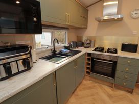 A kitchen with a microwave, stove, sink and cabinets at Seren in Broughton, Cumbria