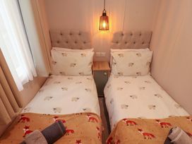 A bedroom with two single beds and a bedside table at Seren, Broughton, Cumbria