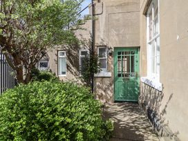A green front door with the number 2 next to a window and bushes in front at Flat 2 The Old Chapel in Whitby