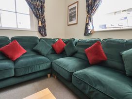 A corner seating area with green sofas and red and green cushions at Flat 2 The Old Chapel in Whitby