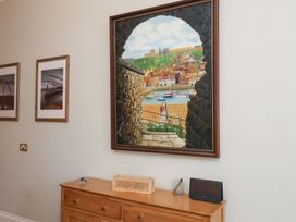 A wooden sideboard below framed paintings hung on a white wall at Flat 2 The Old Chapel in Whitby