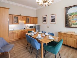 A kitchen with wooden cabinets a dining table set with dishes and chairs and framed pictures on the wall at Flat 2 The Old Chapel in Whitby