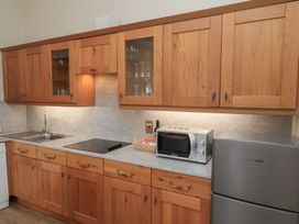 A kitchen with wooden cabinets a microwave a refrigerator a sink and an electric stove at Flat 2 The Old Chapel in Whitby