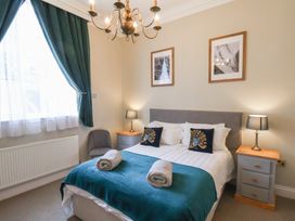 A bedroom with a double bed two bedside tables lamps and a window with curtains at Flat 2 The Old Chapel Whitby