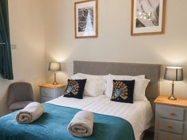 A bedroom with a double bed two bedside tables with lamps two rolled towels on the bed and framed pictures on the wall at Flat 2 The Old Chapel in Whitby