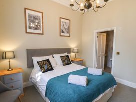 A bedroom with a double bed blue blanket towels two nightstands with lamps two framed pictures on the wall at Flat 2 The Old Chapel in Whitby