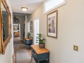 A hallway with wooden tables and plants on them and framed pictures on the walls at Flat 2 The Old Chapel in Whitby