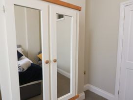 A bedroom reflected in a white wardrobe mirror showing a bed with pillows and a rolled towel at Flat 2 The Old Chapel in Whitby
