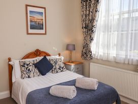 A bedroom with a bed two rolled towels bedside table and a window with curtains at Flat 2 The Old Chapel in Whitby