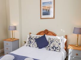 A bedroom with a wooden bed frame white bedding blue patterned pillows two bedside tables with lamps and a framed picture above the bed at Flat 2 The Old Chapel in Whitby
