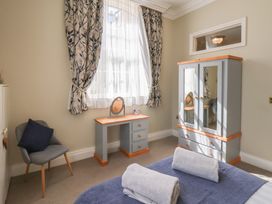 A bedroom with a bed with towels on it a chair a vanity desk and a wardrobe at Flat 2 The Old Chapel in Whitby