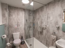 A bathroom with a toilet, shower area with glass door, towel racks, and a sink at Flat 2 The Old Chapel in Whitby