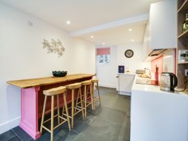 A kitchen with a counter and bar stools at Church Hill House in Port Isaac