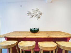 A dining area with a wooden table, stools and decorative fish at Church Hill House Port Isaac