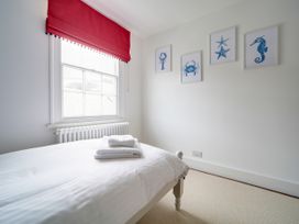 A bedroom with a bed and framed artwork at Church Hill House in Port Isaac