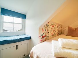 A bedroom with a bed and window seat at Church Hill House in Port Isaac