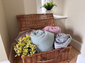 A basket containing rolled blankets and flowers in a living room at The Barn at Grasmere