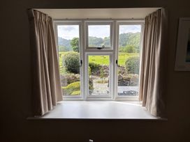 A window with curtains and a view of the garden at The Barn at Grasmere in Grasmere