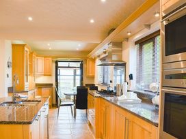 A kitchen with cabinets, countertop, stove and dining table at Cae Coch Brynteg near Benllech