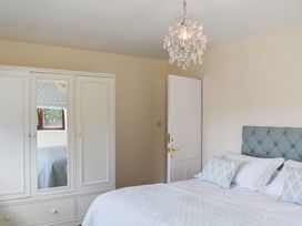 A bedroom featuring a bed, wardrobe, and chandelier at Cae Coch in Brynteg near Benllech