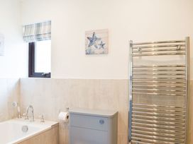 A bathroom with a bath tub and towel warmer at Cae Coch Brynteg near Benllech