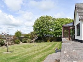 A garden with a house and trees at Cae Coch in Brynteg near Benllech