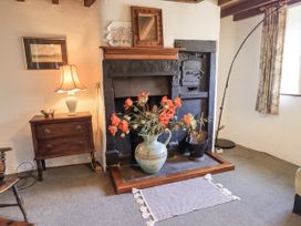 A living room with a fireplace and flowers in a vase at Chapel Cottage in Ennerdale near Cleator Moor