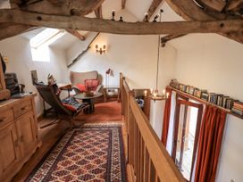 A snug area with a chair, table, and bookshelves at Chapel Cottage Ennerdale near Cleator Moor