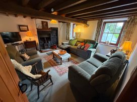 A living room with a sofa, chairs, a coffee table, and a television at Chapel Cottage in Ennerdale