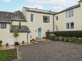 An outdoor view of a house with a gravel area and steps at Swift Barn in Wigton