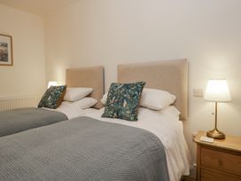 A bedroom with two beds and a bedside lamp at Swift Barn in Wigton