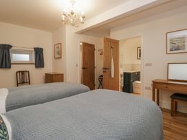 A bedroom with two beds and a doorway to a bathroom at Swift Barn in Wigton