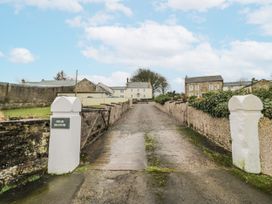 A driveway leading to buildings with a sign at High Manor in Wigton