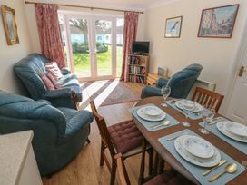 A living area with blue leather sofas dining table set with plates and glasses and glass doors to a garden at Kites - 52 Gower Holiday Village in Scurlage near Port Eynon and Rhossili