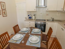 A kitchen with a dining table set for four with plates glasses and cutlery at Kites - 52 Gower Holiday Village in Scurlage near Port Eynon and Rhossili