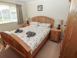 A bedroom with a wooden bed and bedside tables with lamps at Kites - 52 Gower Holiday Village in Scurlage near Port Eynon and Rhossili