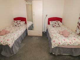 A bedroom with two single beds a wardrobe and a floor lamp at Kites - 52 Gower Holiday Village in Scurlage near Port Eynon and Rhossili
